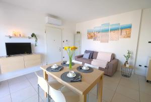 Bilocale in Residence Piazza Brescia في ليدو دي يسولو: غرفة معيشة بها طاولة وأريكة