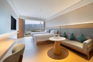a hotel room with a bed and a couch and a table at JI Hotel Hangzhou Xiaoshan Chaoyang Subway Station in Hangzhou