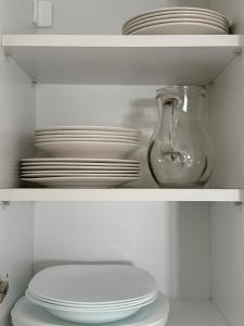 a white shelf with plates and a glass jar and a toilet at Apartman Ilić in Divčibare +8 photos