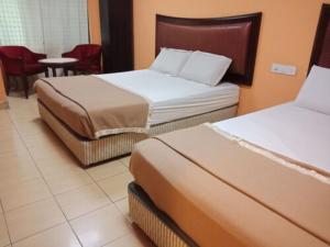 Una habitación de hotel con dos camas y una mesa y sillas. en Hotel Maju, en Sitiawan