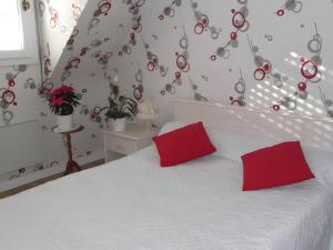 a bedroom with a white bed with red pillows at Chambre d'hote Reine in Cancale