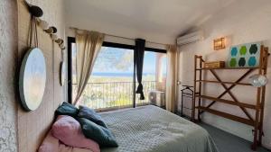 a bedroom with a bed and a large window at Appartement Cocody 215 LUMIO in Lumio