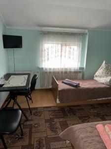 a bedroom with two beds and a desk and a window at ЯВіС in Mamaivci Village