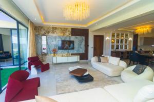 a living room with white furniture and red chairs at Mira Heights Suites & Conferencing Mombasa in Mombasa