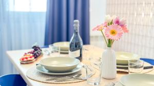 a table with plates and a bottle of wine and flowers at Liam Leo Suite by Ca-Sa Check in Chioggia