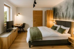 Un dormitorio con una cama y un escritorio con televisión. en Hochthron Suites, 