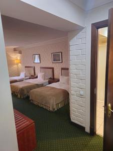 een hotelkamer met 2 bedden en een bakstenen muur bij Arien Plaza in Muruntau