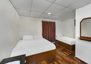 Una pequeña habitación con dos camas y un espejo. en Hotel Maju, en Sitiawan