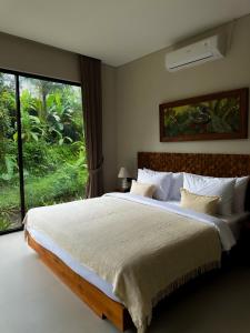 a bedroom with a large bed with a large window at 3BR Tala Villa Ubud in Ubud +42 photos