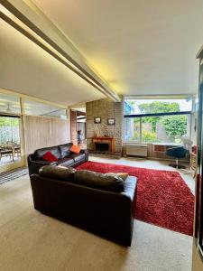 Relax at Tranquil Rye short walk to beach & shops في راي: غرفة معيشة مع أريكة سوداء وسجادة حمراء
