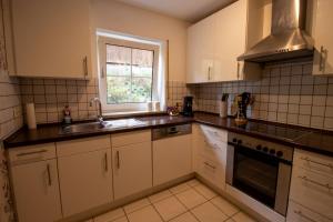 een keuken met witte kasten, een gootsteen en een raam bij Ferienwohnung Josi in Ebermannstadt +7 foto's