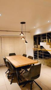 een eetkamer met een houten tafel en stoelen bij Seaside Luxe Blouberg Mansion in Cape Town