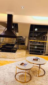 een woonkamer met 2 tafels en een open haard bij Seaside Luxe Blouberg Mansion in Cape Town