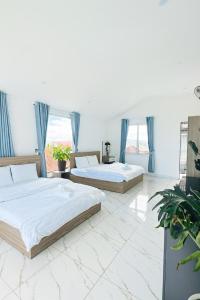 zwei Betten in einem weißen Zimmer mit blauen Vorhängen in der Unterkunft Sunrise Guest House in Da Thanh + 17 Fotos