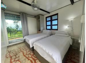 two beds in a bedroom with a large window at OYO 91261 Thebukit, Langkawi in Kuah