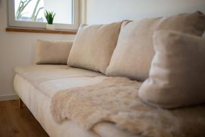 Best Stay Rhöner Gemütlichkeit Dietershausen في كنوزيل: أريكة بيضاء مع وسائد عليها في غرفة المعيشة