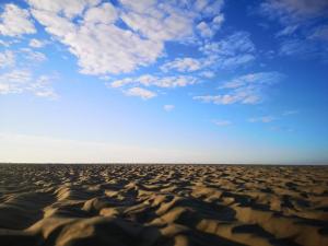 Een afbeelding van een woestijn met een blauwe lucht en wolken. bij 6 person holiday home in Fanø-By Traum in Fanø