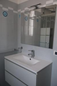 Un baño blanco con lavabo y espejo. en Nottetempo, en Desio