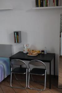 una mesa negra con dos sillas y un plato de comida en Nottetempo, en Desio