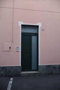 una puerta verde en el lateral de un edificio rosa en Nottetempo, en Desio