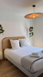 een slaapkamer met een bed met witte lakens en een lamp bij Chambres dans la Villa Larros in Gujan-Mestras