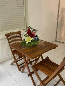 a wooden table with a bouquet of flowers on it at Studio moderne à Saint-François, 38 m² avec piscine in Saint-François