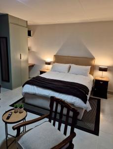 een slaapkamer met een groot bed en een stoel bij Sand & Sea Studio Hermanus in Hermanus