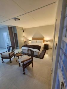 een slaapkamer met een bed, twee stoelen en een tafel bij Sand & Sea Studio Hermanus in Hermanus