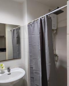 ein Badezimmer mit Duschvorhang und Waschbecken in der Unterkunft Sea Residences Wonders in Manila