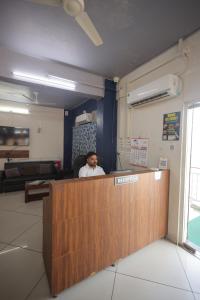 a man sitting at a reception desk in an office at Teja Hotel in Lūnāvāda