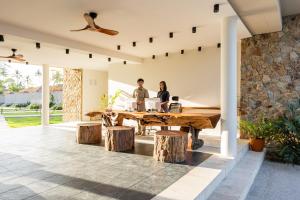 two people sitting at a wooden table in a house at Samaraya Wellness Resort in Amphoe Koh Samui