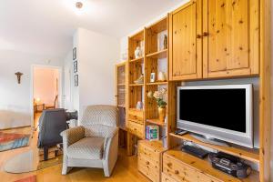 a living room with a television and wooden cabinets at Ferienwohnung am Schmenkenberg in Marsberg