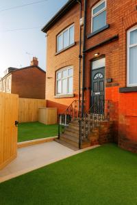 a brick house with a lawn in front of it at Lux 4 Bedroom House - Jacuzzi Bath Sleeps 9 Free Parking Near Leeds Centre in Leeds