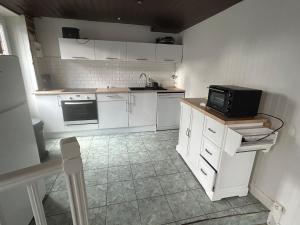 comfortable wooden chalet for family stay في أتيس مو: مطبخ بدولاب أبيض وميكرويف أسود