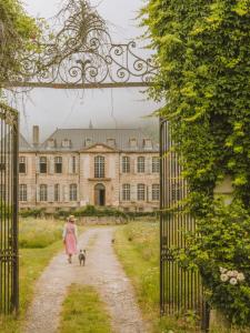 Chateau de Gudanes في Château-Verdun: امرأة تمشي مع كلبها على طول ممر أمام مبنى