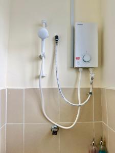 a shower in a bathroom with a white hose at EQAMEL Homestay in Sandakan