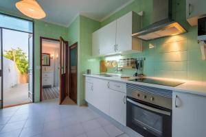 a kitchen with green walls and white cabinets at Sant Miquel in Campanet