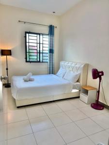 a white bedroom with a bed and a window at EQAMEL Homestay in Sandakan