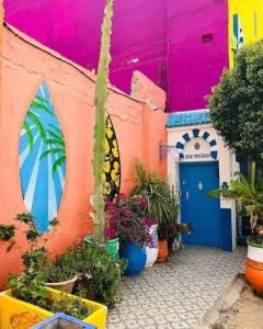 Un edificio colorido con una puerta azul y algunas plantas. en Aghrour Village & Timlaline Dunes Adventure, en Taghazout