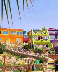 Un grupo de casas coloridas con gente delante de ellas. en Aghrour Village & Timlaline Dunes Adventure, en Taghazout