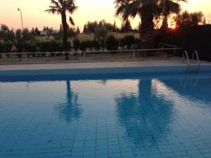 a large blue swimming pool with a sunset in the background at Oasis Room's in Néa Michanióna