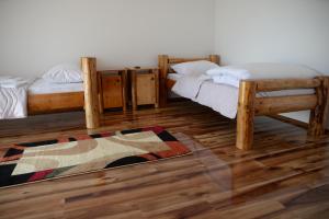 two beds in a room with wooden floors and a rug at Motel Nacionalni Restoran Ognjiste in Koruge