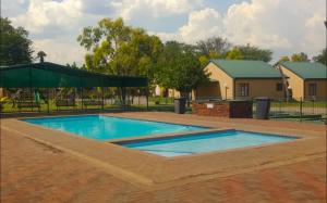 a swimming pool with a green umbrella in a yard at Pendleberry Grove 90 in Bela-Bela