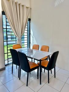 a dining room with a glass table and chairs at EQAMEL Homestay in Sandakan