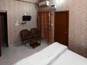 a bedroom with a bed and a chair and a television at Hotel O by OYO Radha Raman Guest House in Rait