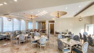 uma sala de jantar com mesas, cadeiras e janelas em Studio BY Jardin Hotels em Indore