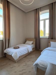 two beds in a room with two windows at Miassine Boutique Hotel in Gyumri