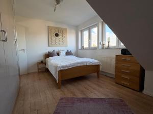 a bedroom with a bed and a dresser and two windows at SkyLoft Rheinland in Bornheim