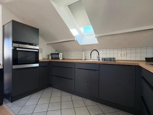 a kitchen with black cabinets and a sink at SkyLoft Rheinland in Bornheim