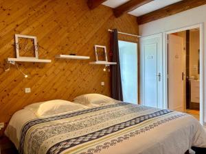 Un dormitorio con una cama y una pared de madera. en La Maison d'Amélina, en Séneujols
